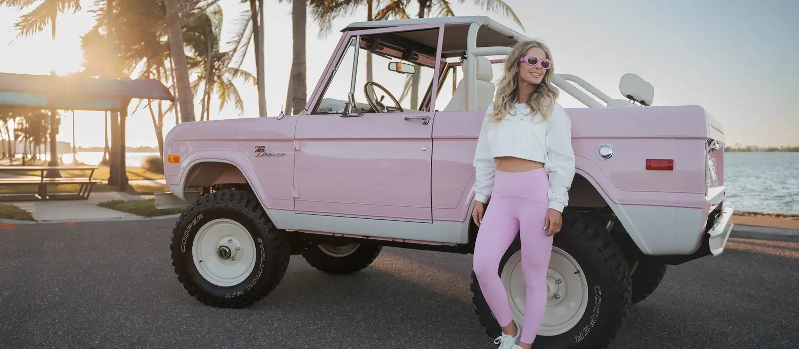 Woman in pink leaning against a Velocity Pink Ford Bronco